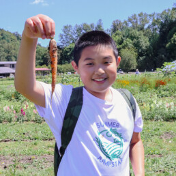 Smiling student holding a freshly harvested carrot at Oxbow.