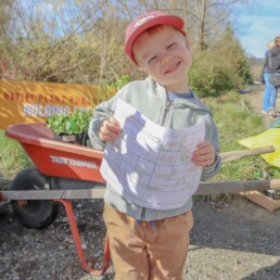 Child holding a nature scavenger hunt sheet during a family activity at the Oxbow Native Plant Festival.