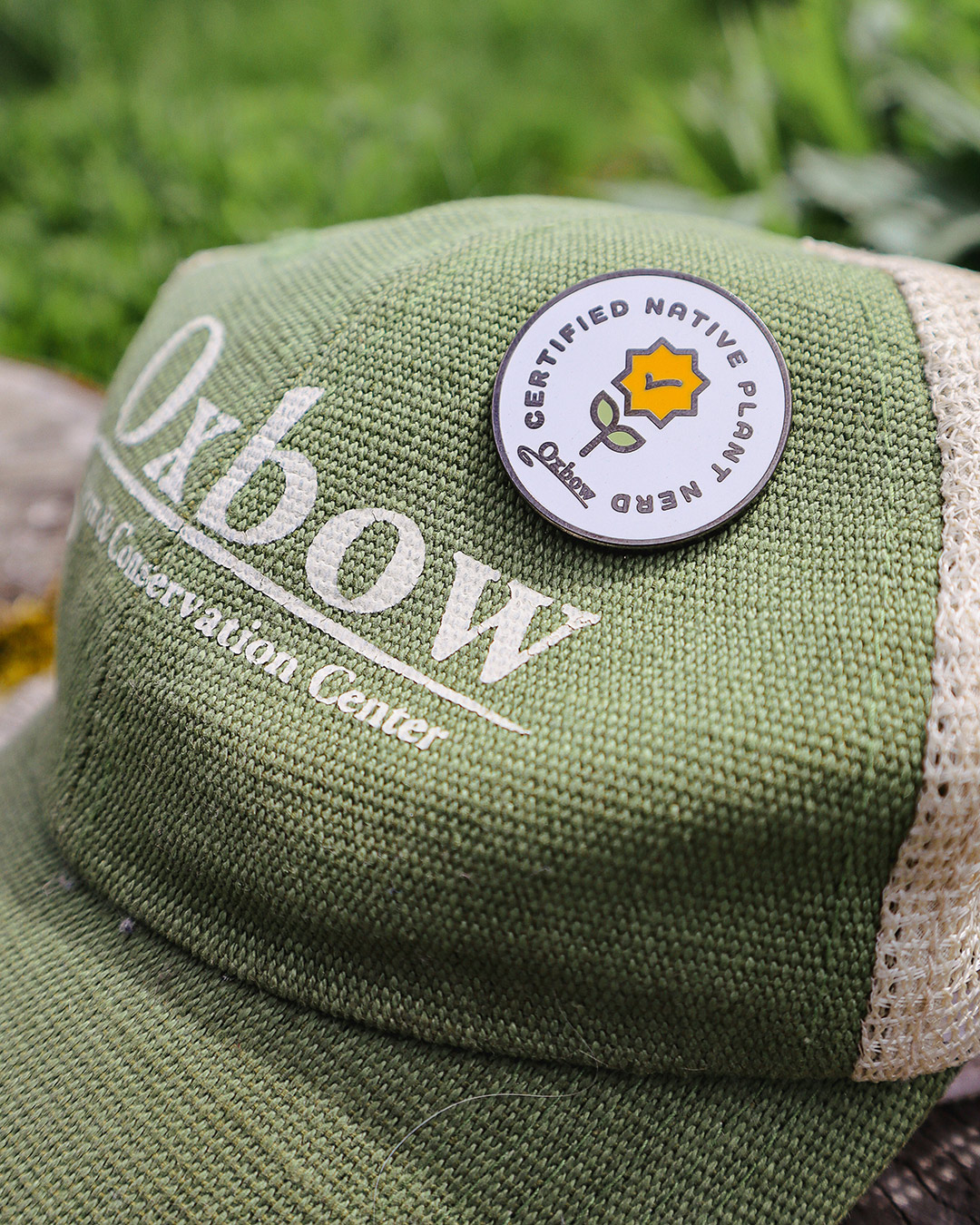 Certified Native Plant Nerd enamel pin displayed on an Oxbow Farm & Conservation Center hat.